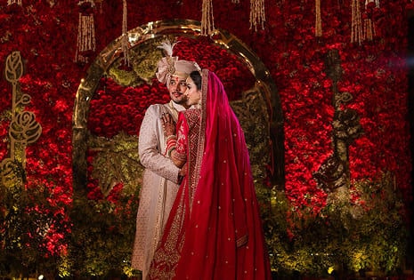 Wedding couple in front of red floral backdrop